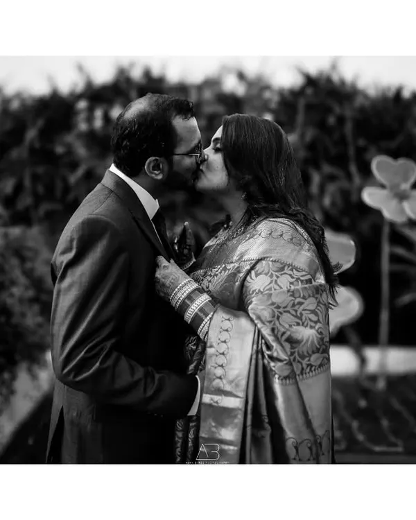 A classic black and white kiss from a post-wedding shoot. The focus is entirely on the couple's intimate moment, creating a powerful and timeless romantic photograph.