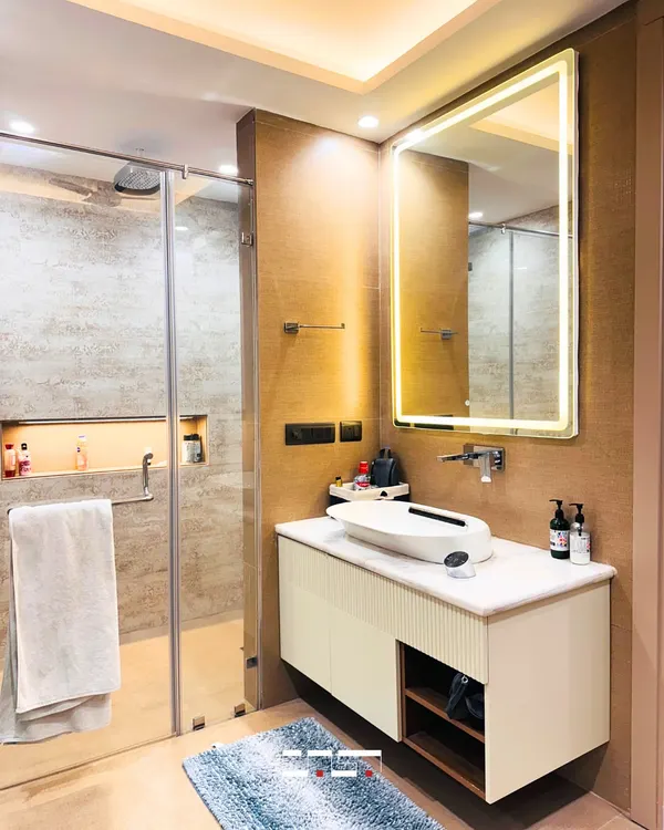 This modern bathroom features a clean, neutral palette with a floating vanity and a large, backlit mirror. The walk-in shower with a glass partition creates a sense of spaciousness and luxury.