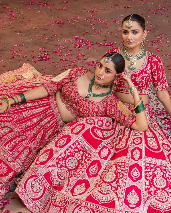 This is the epitome of bridal grandeur. I styled these two brides in magnificent red lehengas, focusing on intricate embroidery that tells a story of tradition. The look is completed with layered emerald and polki jewellery to create a regal, timeless statement for the main wedding ceremony.