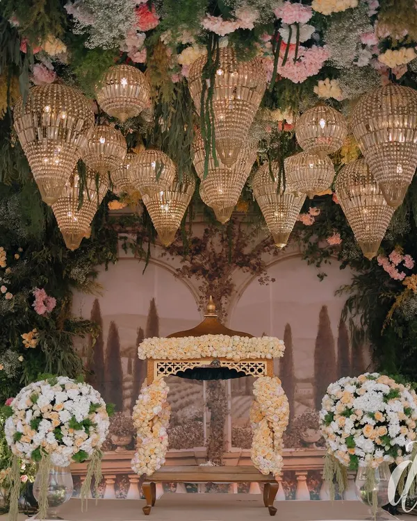 An ethereal Anand Karaj setup featuring a canopy of cascading florals and dozens of crystal chandeliers. The backdrop is a custom-painted mural of a serene landscape, creating a truly magical and otherworldly space for the ceremony.
