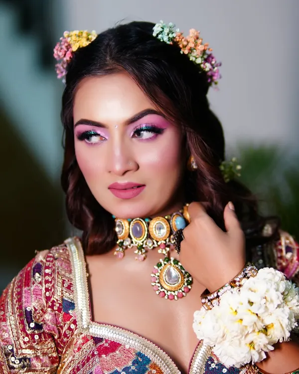 A vibrant and colorful Mehendi look. We used bright pink eyeshadow to match the playful vibe of the event, paired with a floral hair crown.