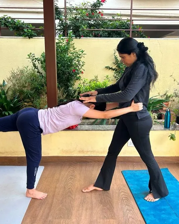A key part of my teaching is providing hands-on adjustments. Here, I am helping a student find the correct alignment in Virabhadrasana III, ensuring her hips are square and her spine is long to maintain balance and stability.