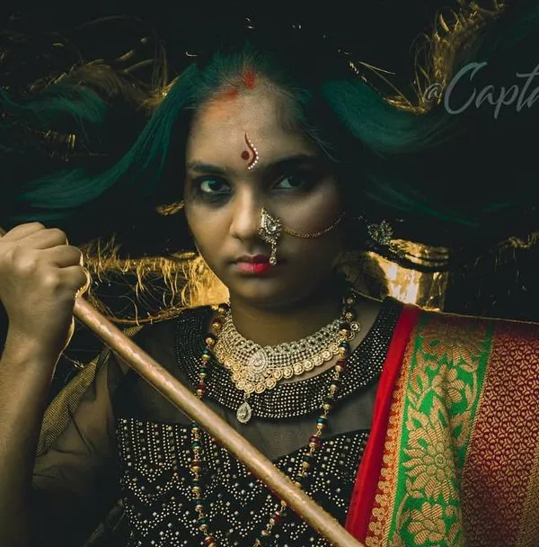 A key image from a conceptual series, this portrait uses a fierce expression and symbolic props to convey strength. The dark, moody lighting and flowing hair create a dramatic, high-impact visual narrative.