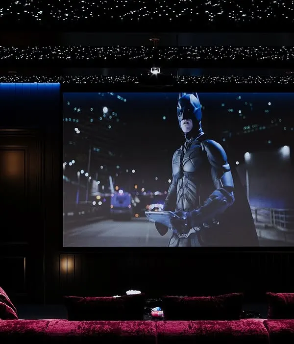 Transform your movie nights with a custom-designed home theater. This space features a large screen, a plush red lounge sofa for ultimate comfort, and a star-like fiber optic ceiling to set the perfect cinematic ambiance.