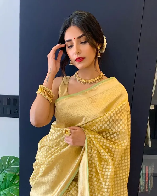 The beautiful actress Harshita Gaur, ready for a friend's wedding. We created a perfect day look with minimalist gold eyes, a classic red lip, and a messy bun with gajra to complement her golden saree.