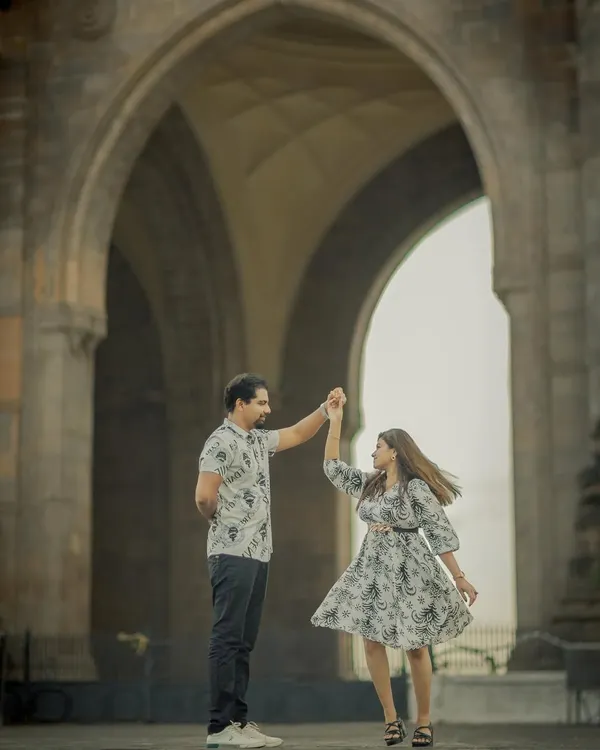 A beautiful, dynamic shot of a couple dancing under the arches of the Gateway of India. This captures the romance and energy of a Mumbai love story.