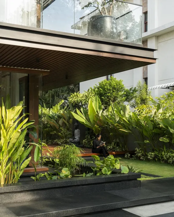 A serene seating nook at Villa re:FORM, nestled within a lush garden and sheltered by the overhead balcony, exemplifying our tropical modern style.