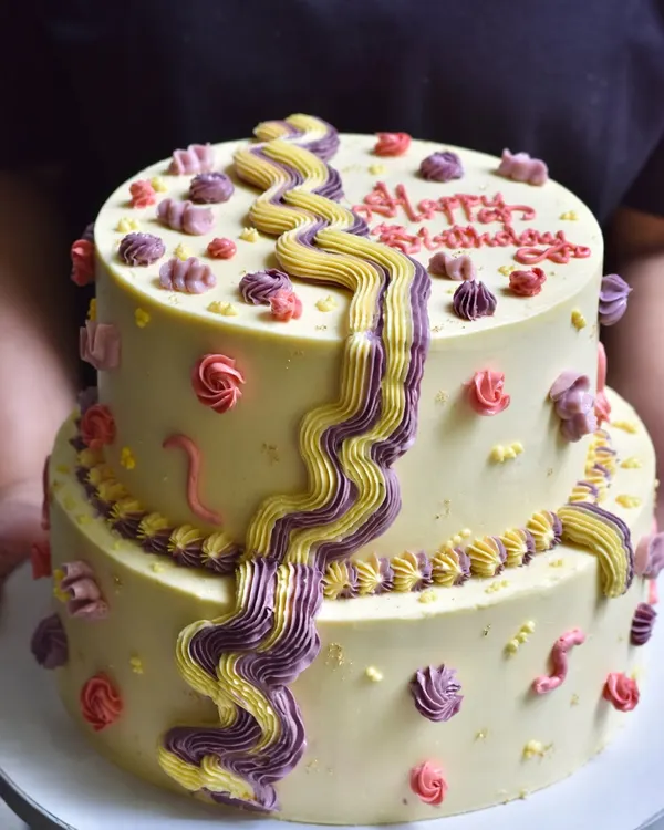 A fun and playful two-tiered birthday cake with whimsical purple and yellow buttercream swirls. This custom design is perfect for a vibrant and energetic celebration for kids or the young at heart.