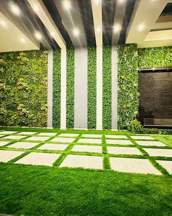 This is one of our signature indoor installations, transforming a large space into a serene green lounge. We combined high-density artificial turf with custom stone pavers, floor-to-ceiling vertical gardens, and an integrated water feature to create a truly luxurious, maintenance-free environment.