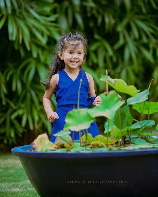 A candid moment of pure joy. This little girl's happy smile as she plays near a lotus pond in a garden is what outdoor photography is all about.