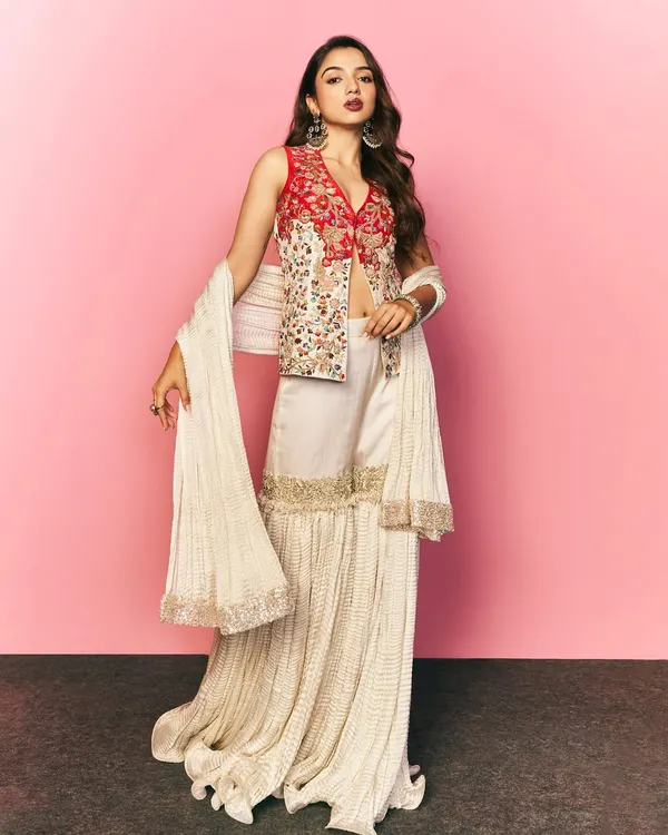 A full length shot of Ahsaas Channa styled for a Myntra festive campaign. This modern ethnic look features a sharara with a beautifully embroidered red jacket, perfect for festive occasions.