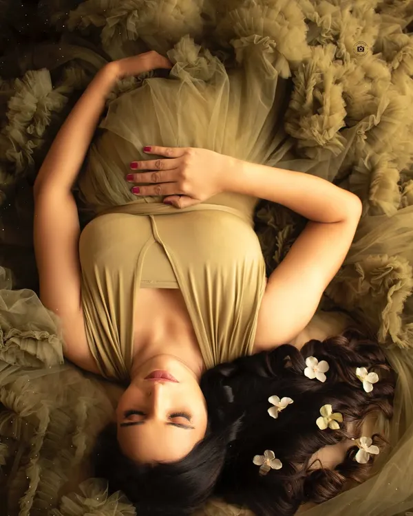 A serene portrait of a mother-to-be, resting peacefully in an olive green gown. This shot is all about capturing that quiet, powerful connection with your baby.