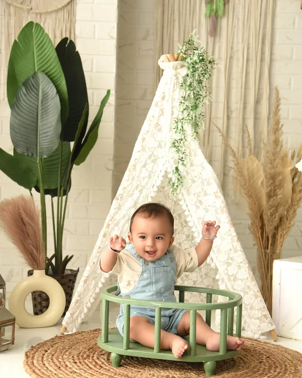A joyful, hands-in-the-air moment during a boho-themed sitter session. The natural elements like the teepee and plants create a calming and beautiful environment.