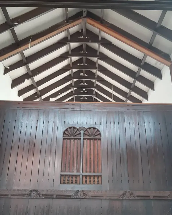 The interior of a traditional home during restoration, showcasing the original exposed wooden rafters and intricately carved wall panels. My goal is to protect and highlight these irreplaceable heritage details.