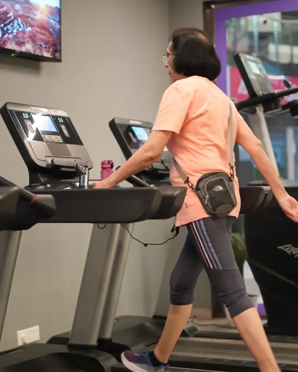 Age is no barrier to fitness. An elderly member enjoys a steady-paced walk on one of our premium Life Fitness treadmills.