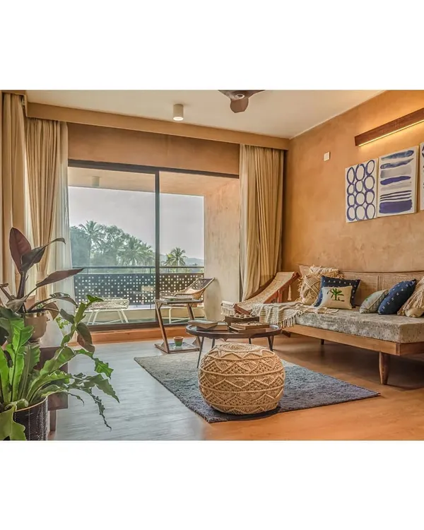 The living room of a villa at Svamitva Terravana, featuring lime-plastered walls and natural Kota stone flooring. The large sliding doors open to the outdoors, blurring the boundary between the interior and the landscape.