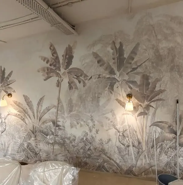 A wide view of the large-scale jungle mural during installation. This type of custom wallpaper can cover entire walls, creating an immersive and impressive natural scene.