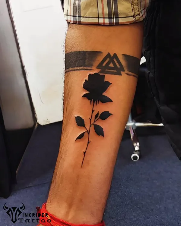 We covered an old tattoo with this bold black rose and armband design. The negative space technique makes the rose pop, completely concealing what was underneath.