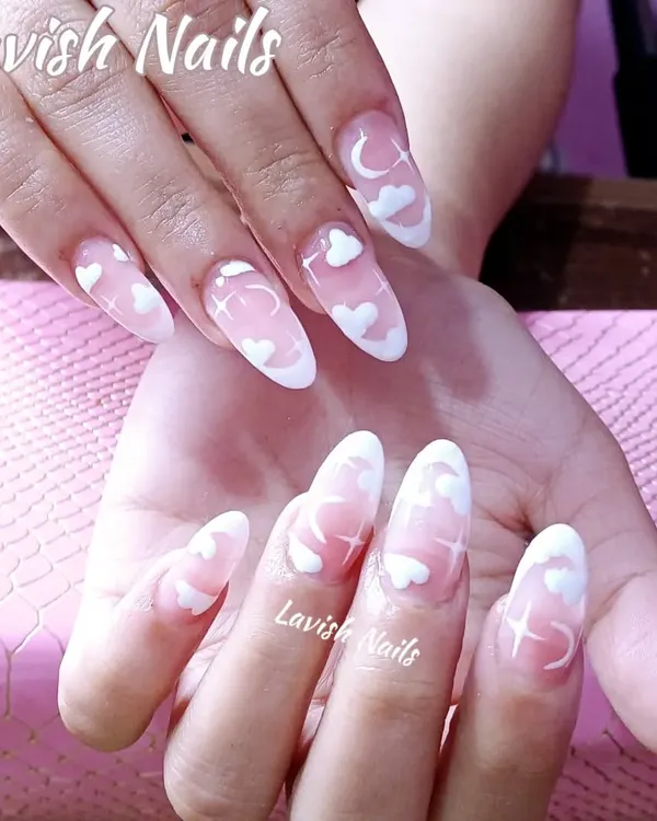 A dreamy and whimsical set of long, clear polygel nails with hand-painted white clouds, moons, and stars.