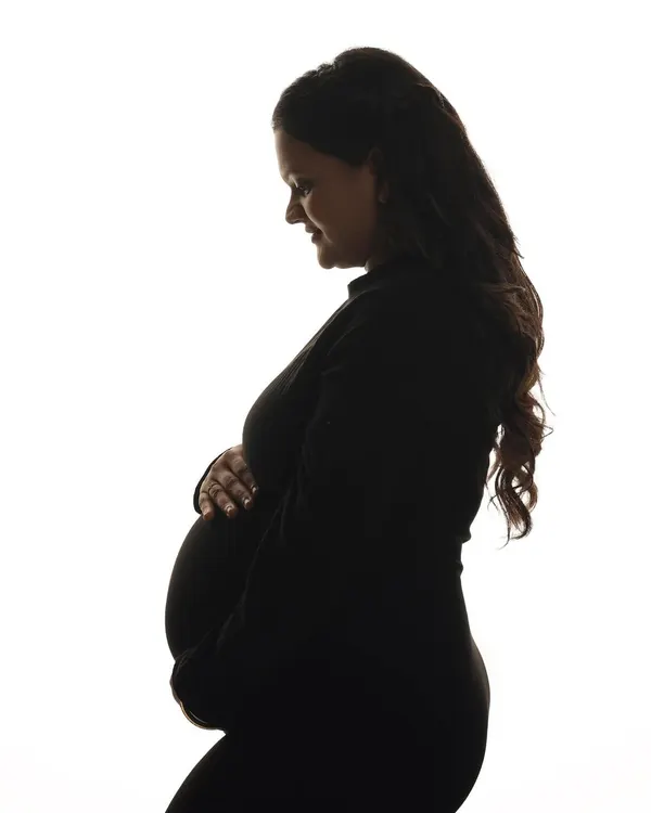 A classic black and white silhouette portrait. This timeless style focuses on the beautiful outline of the baby bump, creating a simple yet powerful and artistic image.