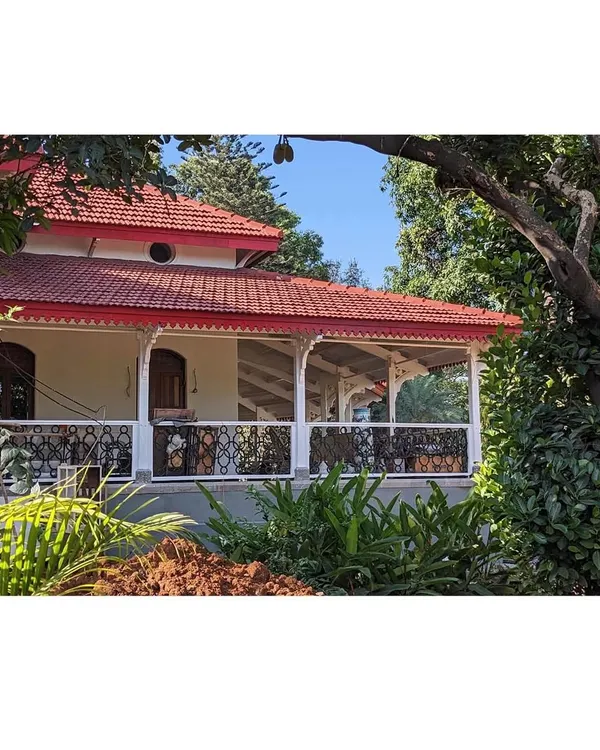The restored front porch, nestled amongst lush greenery. We brought back the original charm of the decorative railings and pillars, creating an inviting entrance that honors the building's century-old heritage.