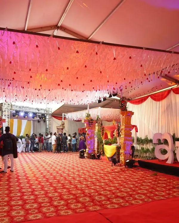 A wide view of the main event hall for the Zee Kannada awards, showing the large stage, patterned red carpet, and elegant ceiling decor with hanging white tassels and soft lighting.