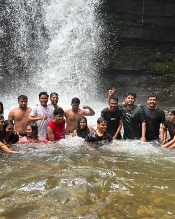 A group of trekkers enjoying a refreshing dip in a waterfall pool during the Nethravathi trek.