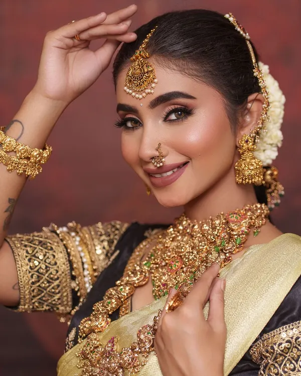 This is the quintessential South Indian bridal look I adore. The intricate temple jewellery, with its antique gold finish and detailed carvings, feels so timeless and perfect for the main ceremony. This set includes a stunning choker, a longer haram, matching jhumkas, and a maang tikka that completes the look.
