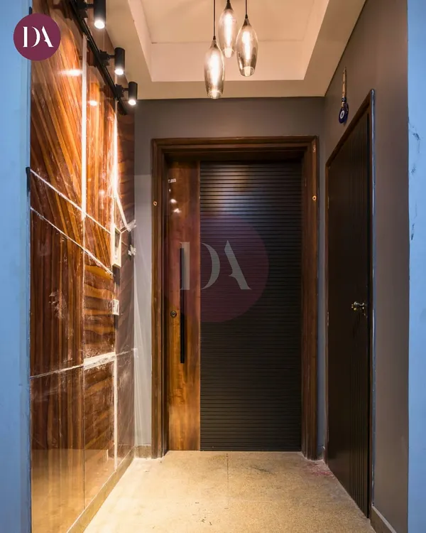 The entrance to this home makes a statement with a mix of rich textures. I used a glossy, wood-grain panel with inlaid details next to a modern, ribbed black door. The pendant lights add a final touch of drama.