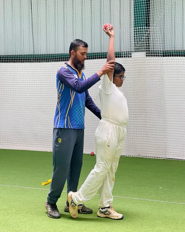 Our coaches provide hands-on guidance to perfect every aspect of the game. Here, a coach corrects a young bowler's arm position to ensure a clean, effective, and injury-free action.