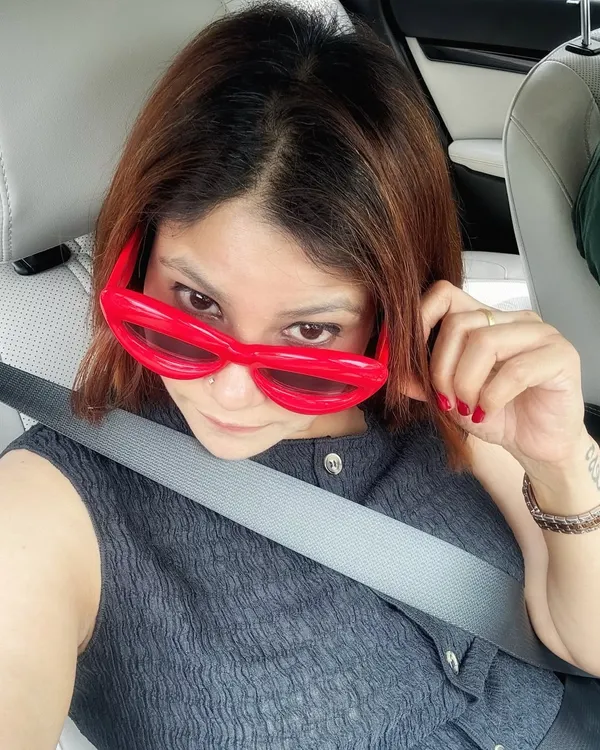 Accessories can be the main event. These quirky, oversized red sunglasses add a dose of fun and chaos to an otherwise calm and neutral outfit, proving that a single accessory can change your entire vibe.