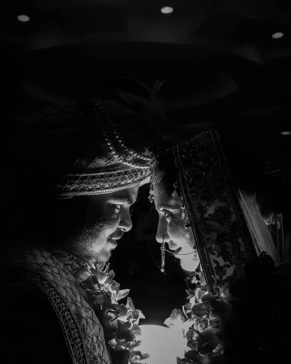 A powerful black and white shot capturing the bride and groom in a moment of intense connection. The dramatic lighting focuses on their faces, creating a timeless and deeply emotional wedding portrait.