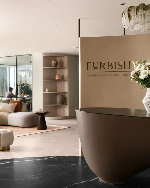 The entrance to our Hyderabad studio, featuring our custom-designed curved reception desk and prominent branding. This view shows the transition from the black marble flooring to the living area, setting a tone of modern, sculptural elegance right from the first step.