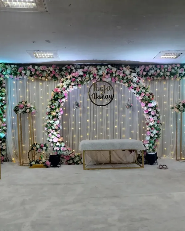 This is one of our most popular engagement and sakharpuda setups. The full floral arch, elegant white drapes with fairy lights, and a custom name hoop create a perfect, photo-ready backdrop for your special day.
