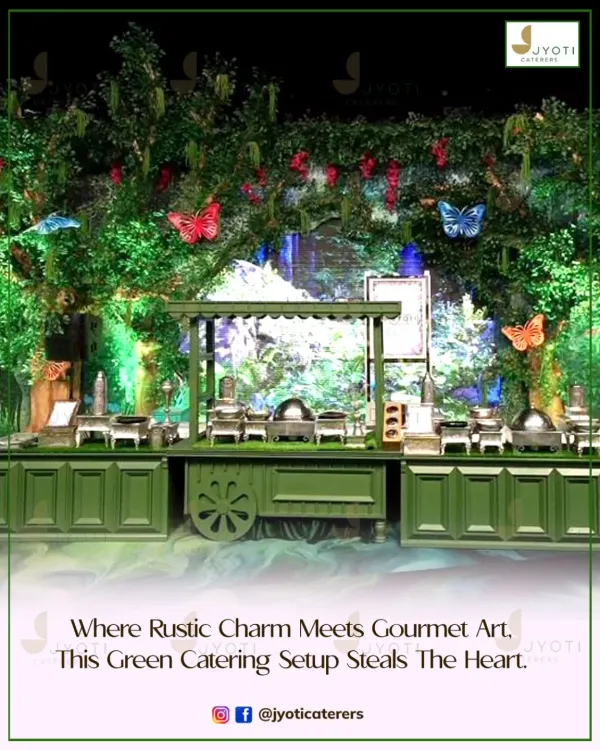 A rustic-themed catering setup where lush greenery and butterfly details create an enchanting forest feel. The green wooden cart and counters blend seamlessly with the natural decor.