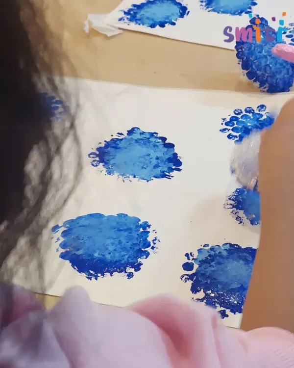 A child uses bubble wrap to create beautiful blue hydrangea blossom prints. This tactile art activity is a fun and creative way to explore textures and patterns.