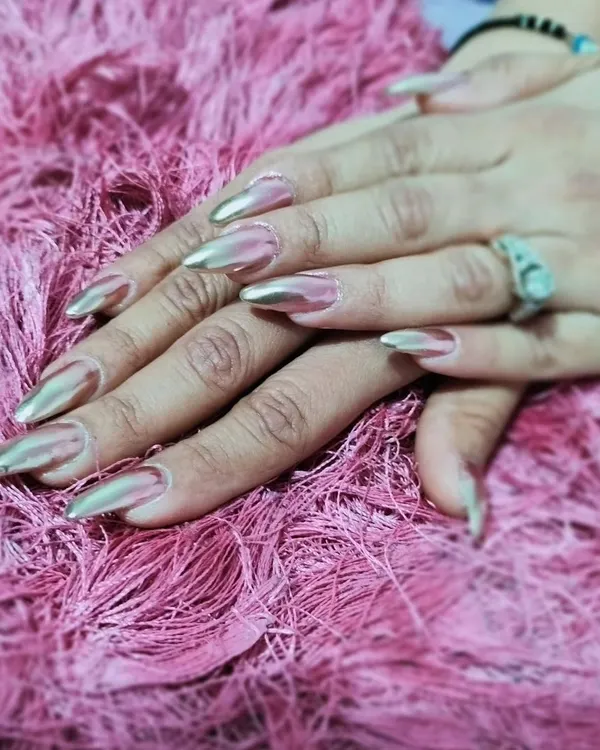 A full set of long, pointed stiletto nails with a stunning, high-shine metallic silver chrome finish for a futuristic and edgy look.