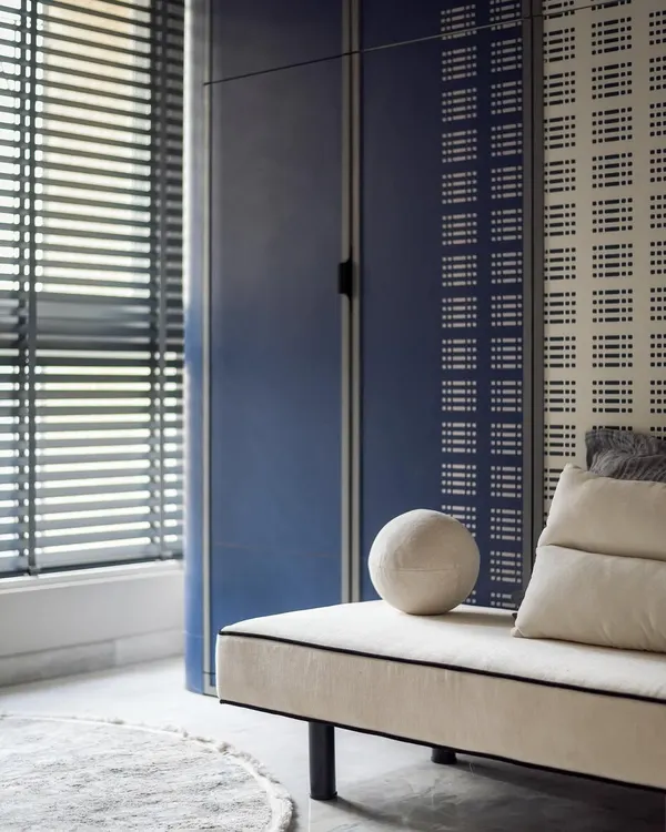 This children's room was designed with space-saving solutions like a Murphy bed to maximize play area. The blue and white color scheme is fresh and modern, with custom perforated wardrobe doors adding a unique touch.
