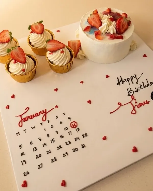 A truly personal birthday gift. This custom creation features a hand-piped calendar marking the special day, alongside a mini cake and fresh strawberry cupcakes.