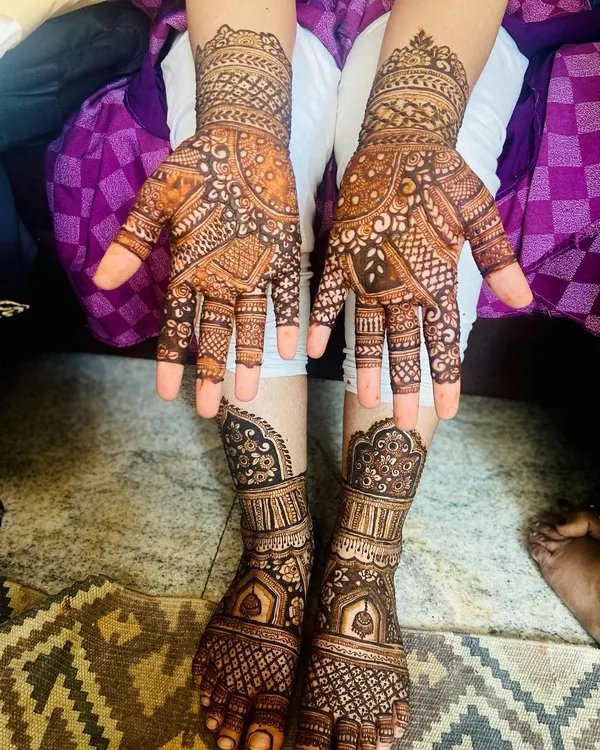 A full view of a stunning bridal mehendi set after the henna paste has dried. The designs on the hands and feet are created to match, featuring traditional Indian motifs for a cohesive and beautiful bridal look.