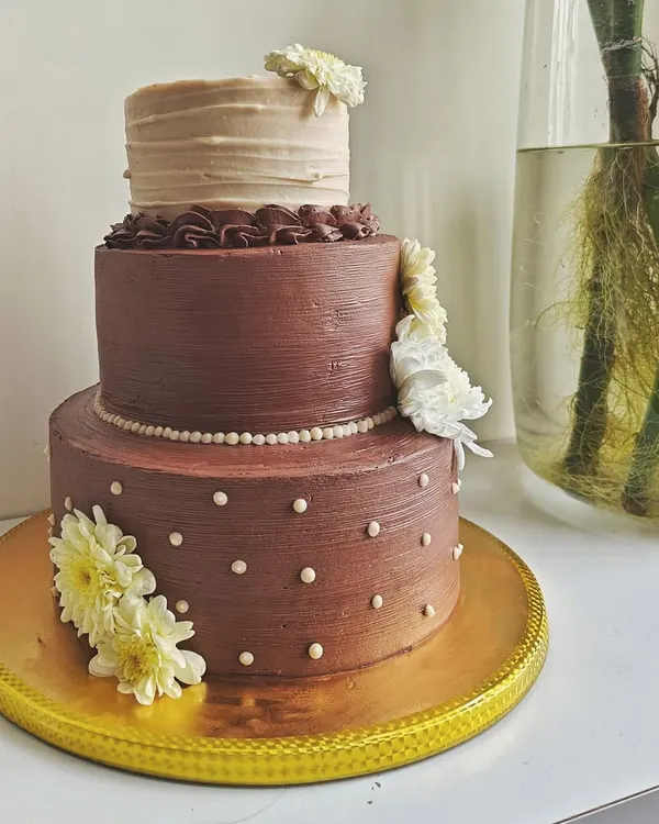 This three-tiered chocolate wedding cake was designed to be both rustic and elegant. Each tier has a different texture, and it's adorned with fresh white flowers for a touch of natural beauty.