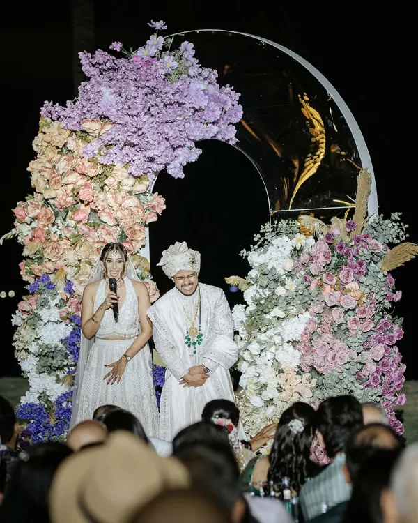 The couple addresses their guests after the wedding ceremony. This is a beautiful moment of gratitude and shared joy, with the stunning floral arch framing them perfectly.