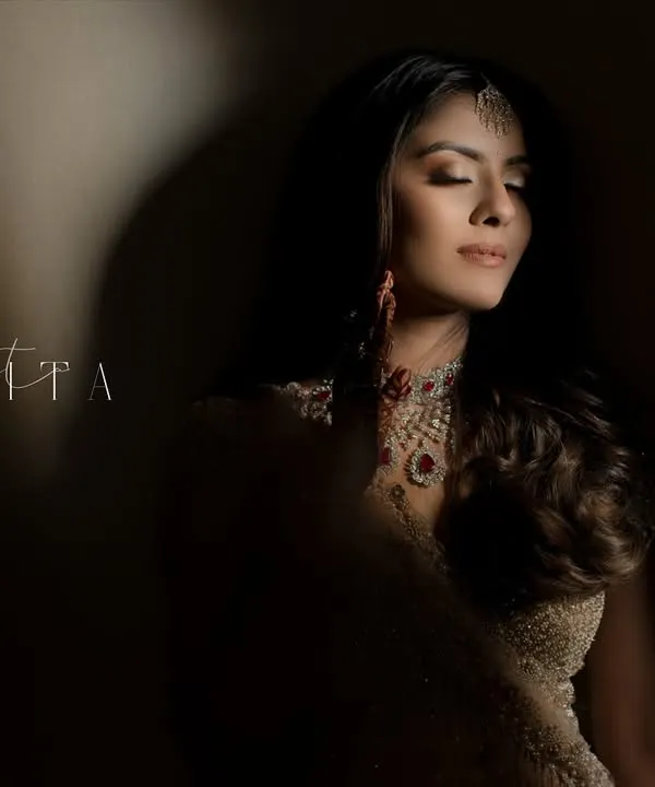 A moment of quiet contemplation for the bride. The dramatic play of light and shadow creates a powerful, artistic portrait that highlights her serene beauty and intricate jewelry.