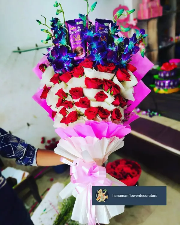 I love creating bouquets that are also a complete gift. This arrangement combines classic red and white roses with exotic blue orchids and includes Cadbury Silk chocolates nestled among the blooms, all wrapped beautifully.