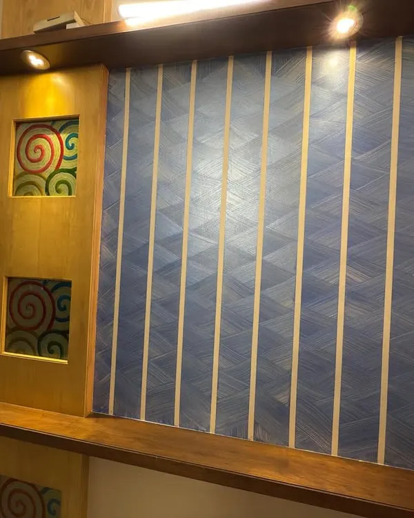 A finished accent wall combining multiple techniques. We used painter's tape to create a geometric pattern over a blue textured base, next to a wooden panel with custom art inserts.