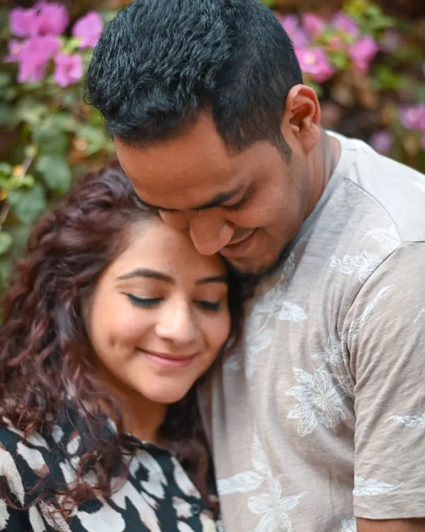 A close-up shot capturing a moment of pure contentment. The gentle lean and happy smiles show the comfort and security this couple finds in each other as they await their baby.