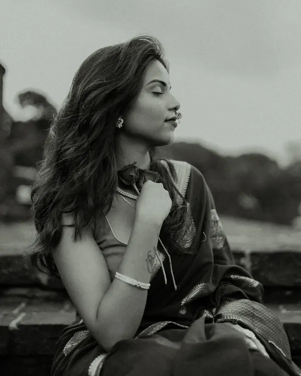 A serene black and white portrait. The model's calm expression and the soft focus on her tattoo create a personal and introspective mood, enhanced by the classic monochrome finish.