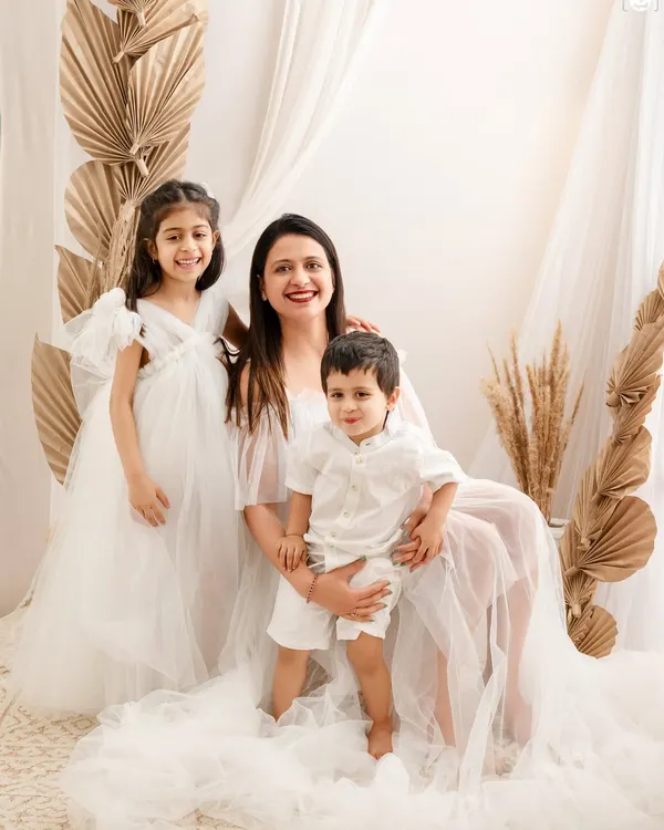 A serene portrait of a mother with her two children. The all-white theme and soft, dreamy setup create an angelic and timeless image that highlights their close bond.