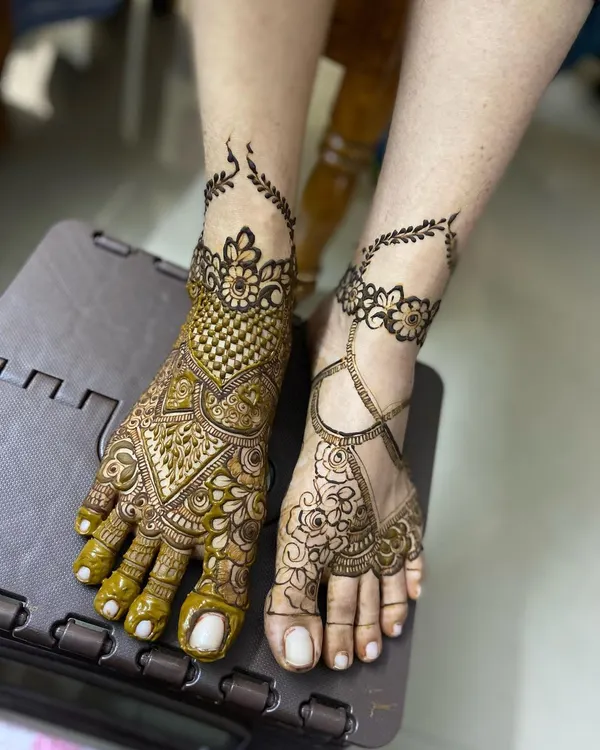 An example of asymmetrical feet mehendi, with one foot heavily decorated in a traditional style and the other featuring a lighter, jewellery-like design.