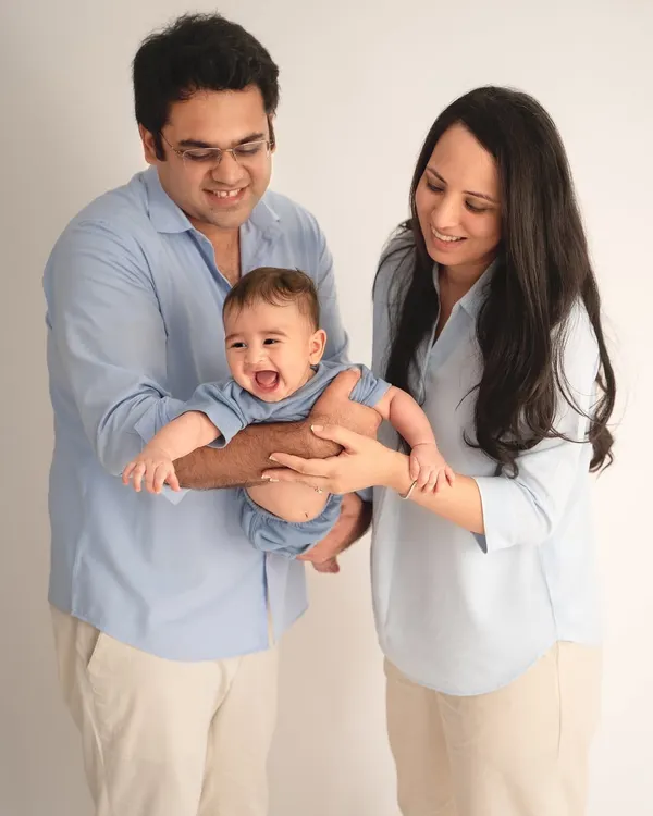 The pure joy of a baby's laughter is contagious. In this studio family portrait, the parents are completely focused on their happy baby, creating a candid and heartwarming shot.